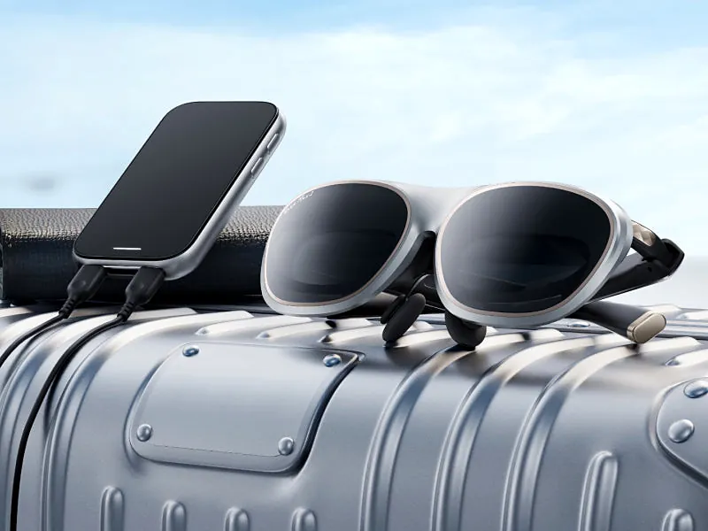 Rokid Max 2 glasses and Station 2 hub resting on an aluminum suitcase, connected by a USB-C cable
